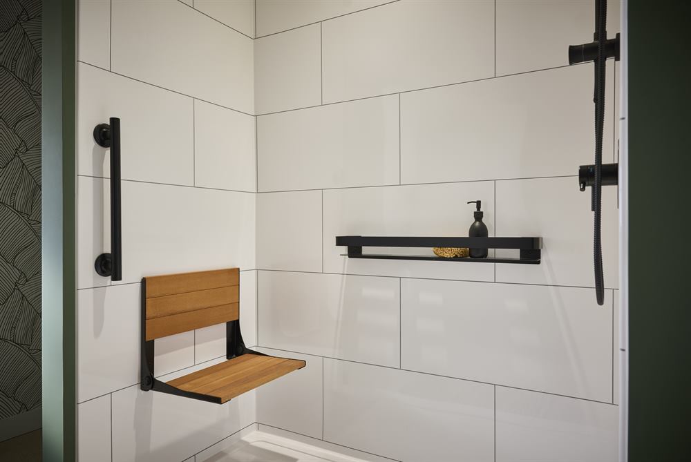 Fold-down teak shower seat and matte black grab bar styled as part of the design